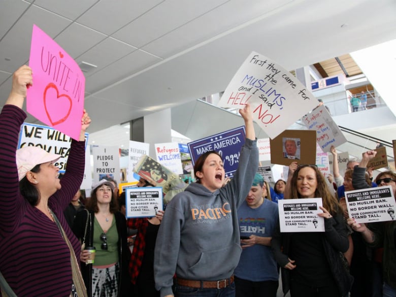 Protesters hold signs at Sacramento International Airport on January 29, 2017, at a demonstration against President Trump's executive order banning travel to the U.S. for refugees and immigrants from seven countries.